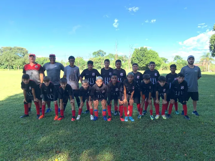 Atletas e equipe técnica reunidos lado a lado no gramado.